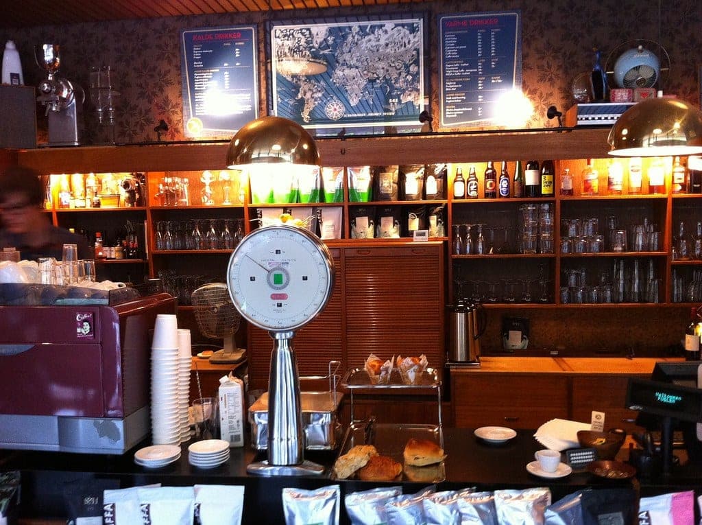 Interior of Fuglen café in Oslo, with mid-century furnishings and brass mushroom pendant lamps over the counter.